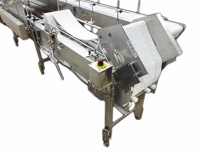 Stainless steel food processing conveyor carrying products through a sanitary production line